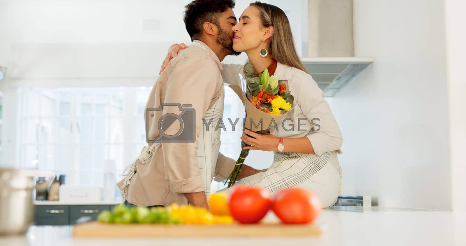 Royalty free image of Couple love, flowers and happy cooking together in kitchen at home, romance and celebrate relationship bonding. Married man and woman smile, surprise bouquet and happiness care in family house by YuriArcurs