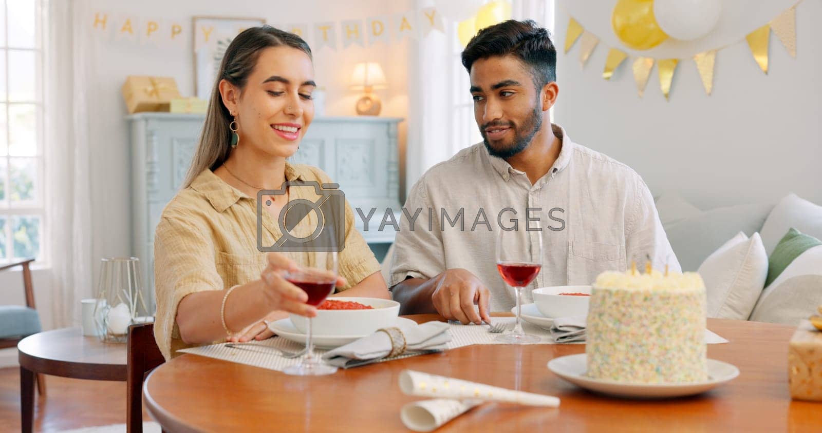 Royalty free image of Gift, dinner and couple talking about birthday, anniversary or celebration at a dining room table in house. Happy, smile and young man and woman speaking about present, gratitude and love with food by YuriArcurs