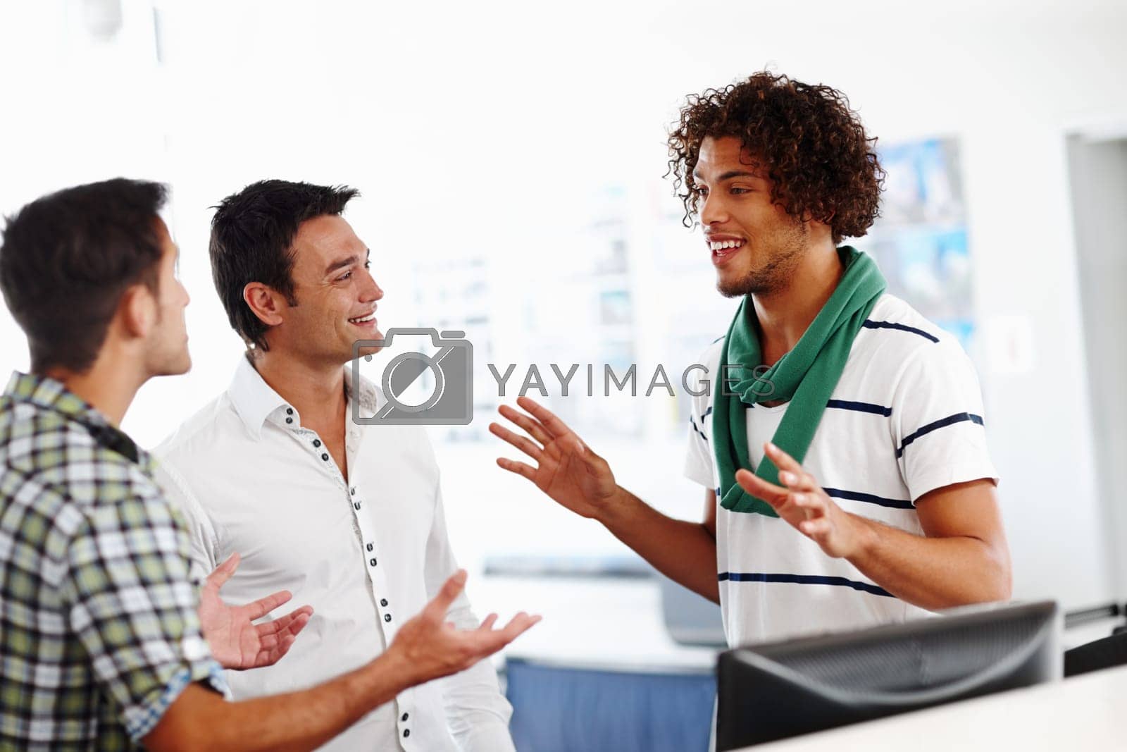 Royalty free image of Just listen to my idea...Three male colleagues working in the office together. by YuriArcurs