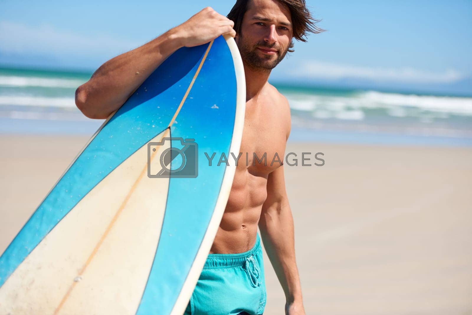 Royalty free image of Hes ready to surf. A young man leaning on his surfboard looking at the camera. by YuriArcurs