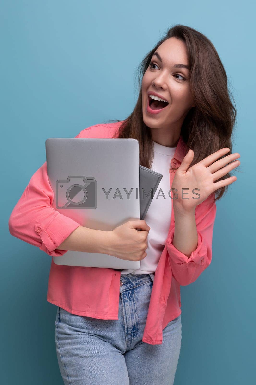 Royalty free image of positive successful freelance brunette young woman in shirt and jeans with laptop by TRMK