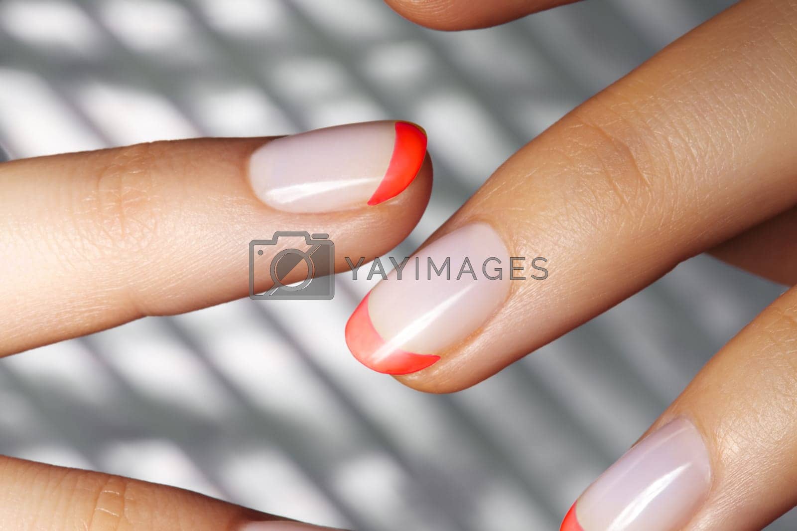 Royalty free image of Hands with bright Red French Manicure on Geometric Background. Nails Art Design. Close-up of Female Hands with Trendy Neon Nails on Silver Striped Print Background by MarinaFrost