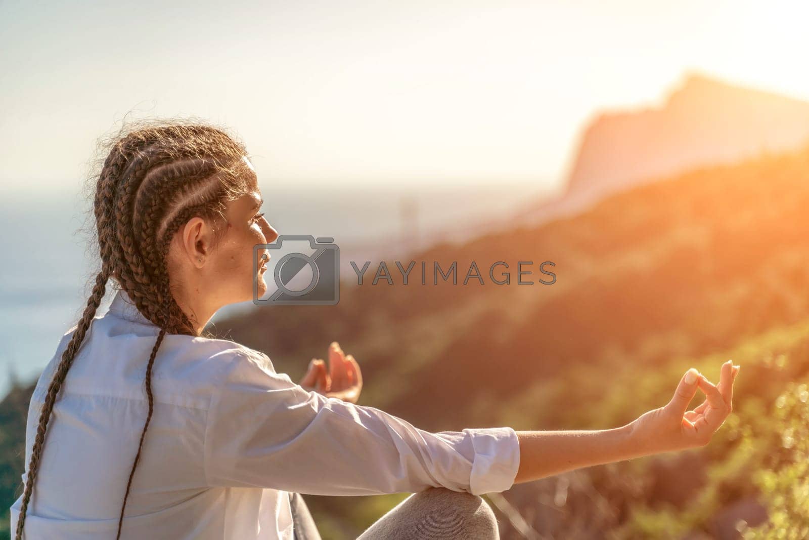 Royalty free image of Yoga woman mountains. Profile of a woman doing yoga in the top of a cliff in the mountain. Woman meditates in yoga asana Padmasana by Matiunina