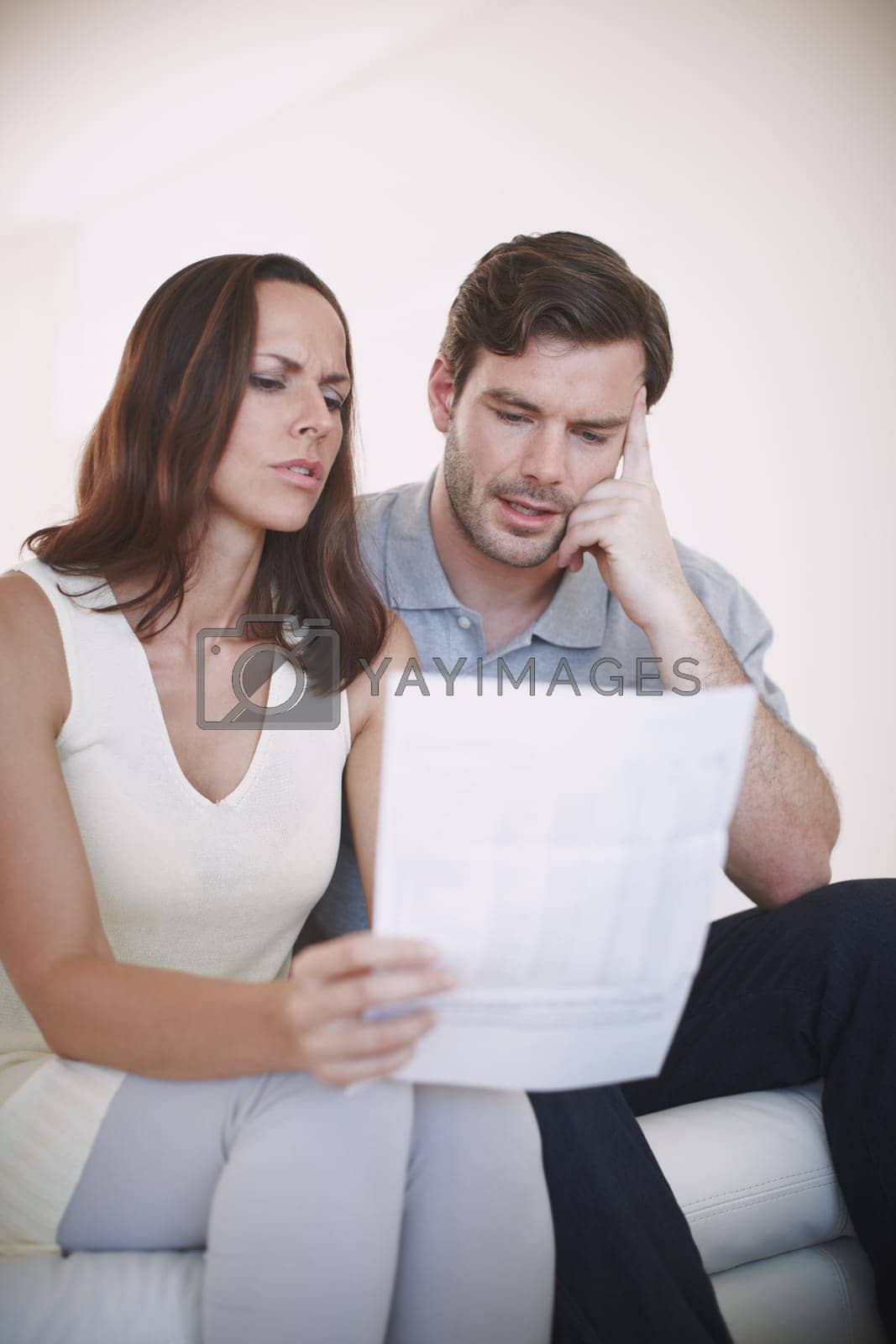 Royalty free image of This is going to be a tough month...A married couple having a serious discussion about their home finances while inspecting a bill. by YuriArcurs