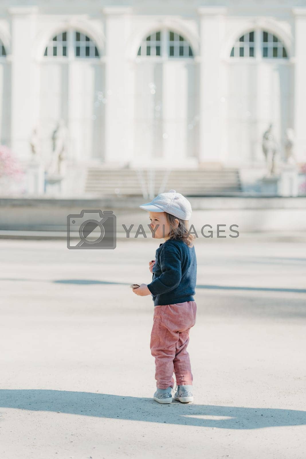 Royalty free image of A female toddler with her back in the yard of the European palace. by RomanJRoyce