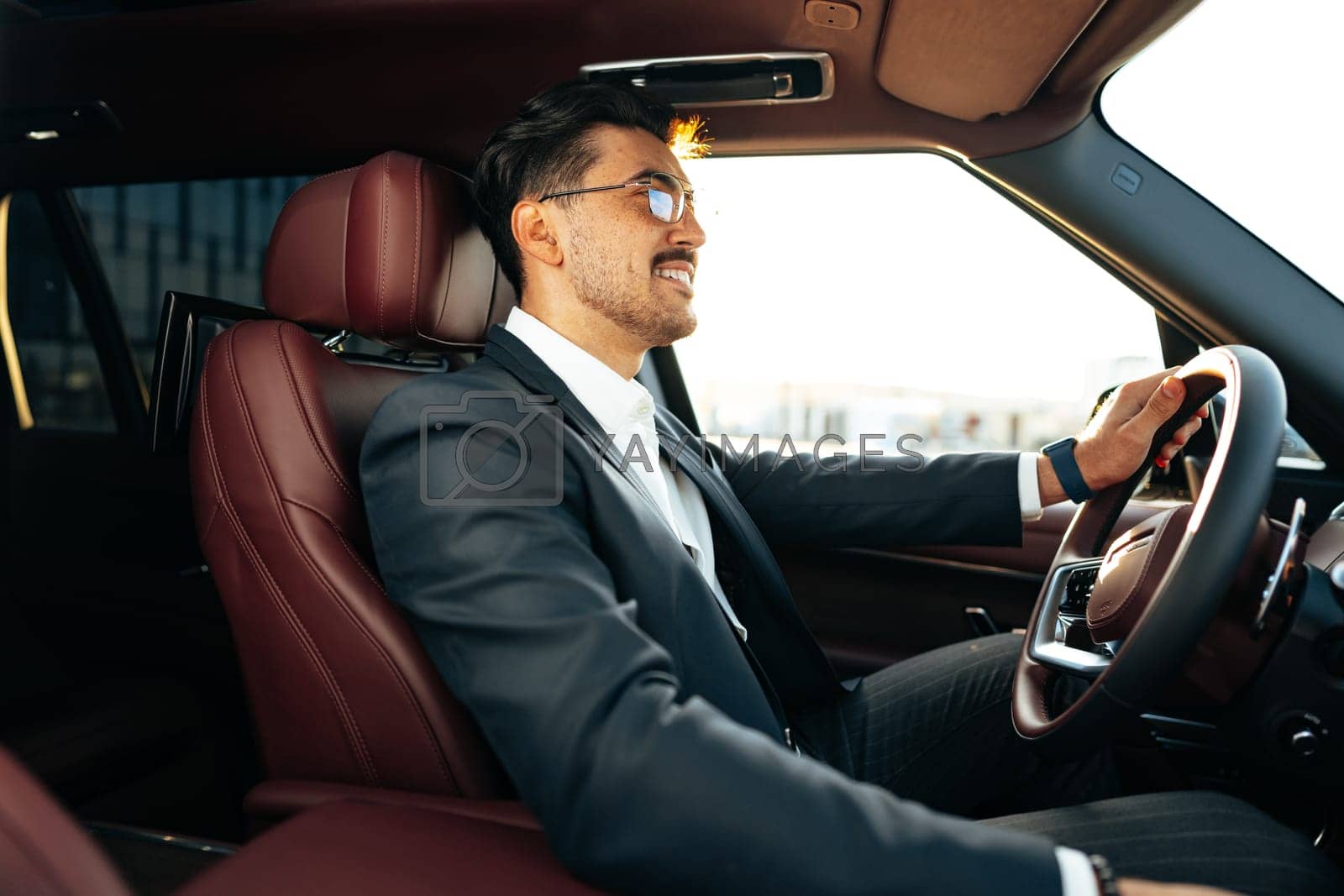 Royalty free image of Young businessman in elegant suit driving luxury car by Fabrikasimf