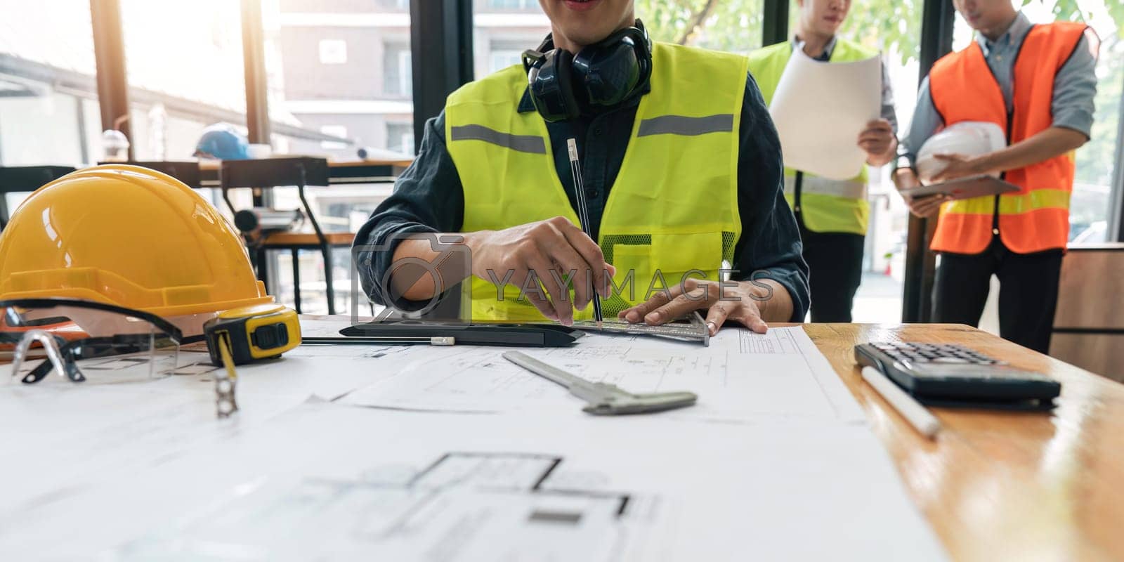 Royalty free image of engineer working on blueprints and construction plans. Building engineers calculate and draft building construction drawings, civil engineering, and construction business concepts by nateemee