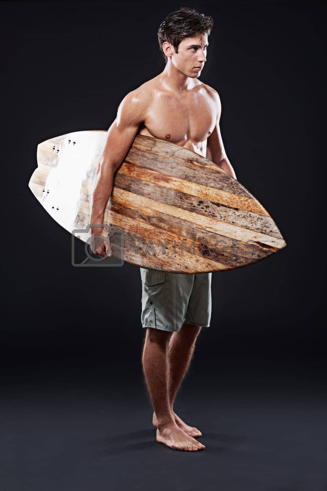 Royalty free image of Lets cruise some waves. Full length studio shot of a young surfer with a vintage board. by YuriArcurs