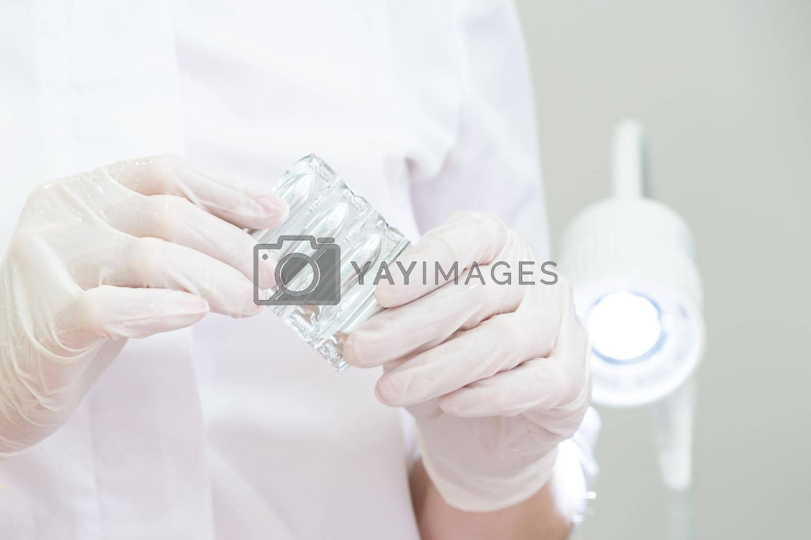 Royalty free image of Doctor wearing medical gloves holding a pack of rectal or vaginal suppositories by Mariakray