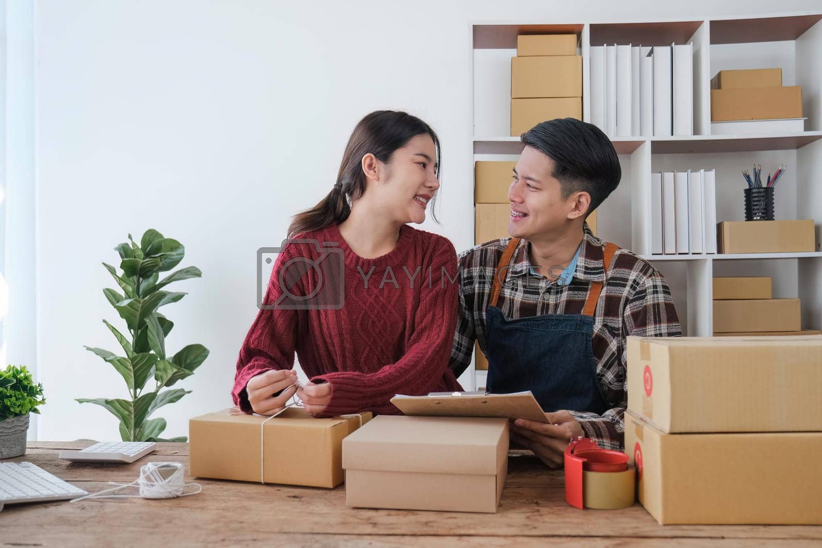 Royalty free image of startup small business owner working with computer at workplace. freelance man and woman seller check product order, packing goods for delivery to customer. Online selling, e-commerce by nateemee