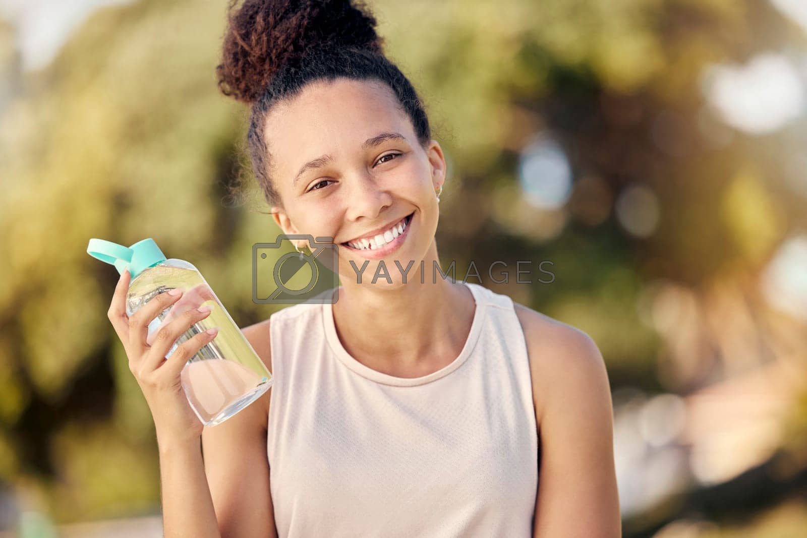 Royalty free image of Water bottle, fitness and nature of black woman in portrait for outdoor exercise, wellness and healthy diet lifestyle in park or forest. Trees bokeh, workout and sports girl with drinking water gear by YuriArcurs