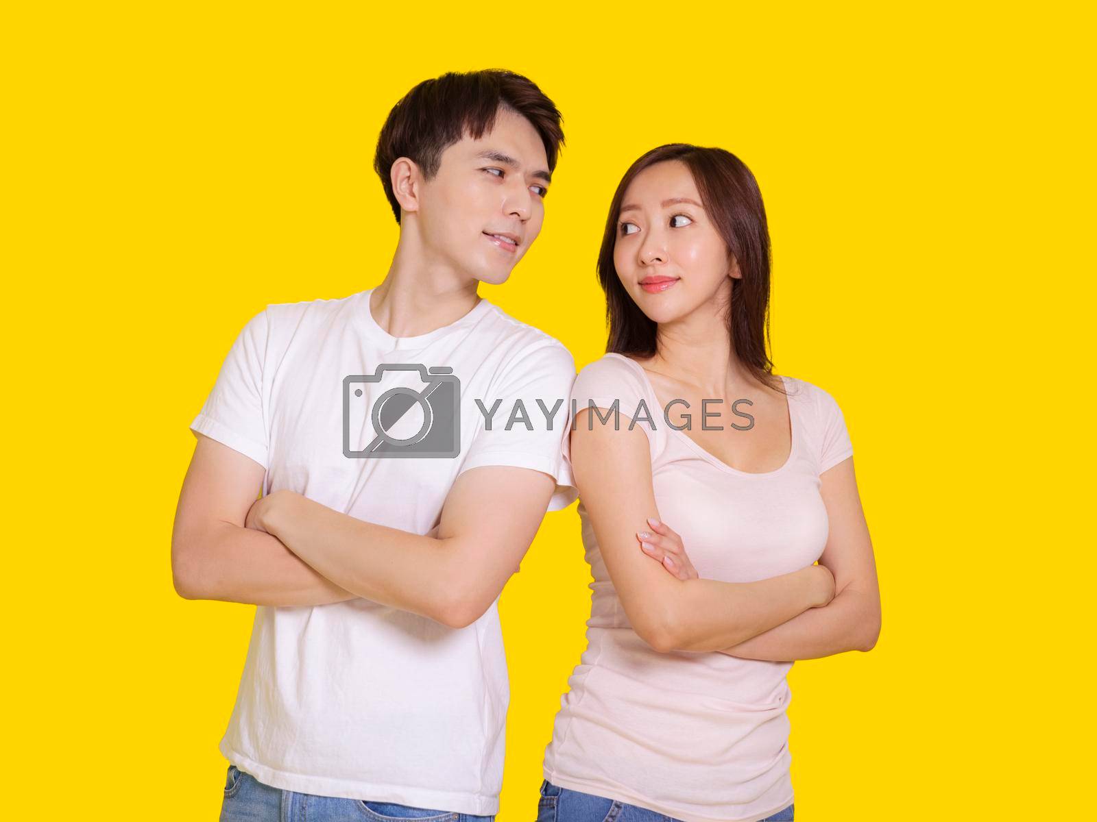 Royalty free image of Happy young couple standing with arms crossed.Isolated on yellow background. by tomwang