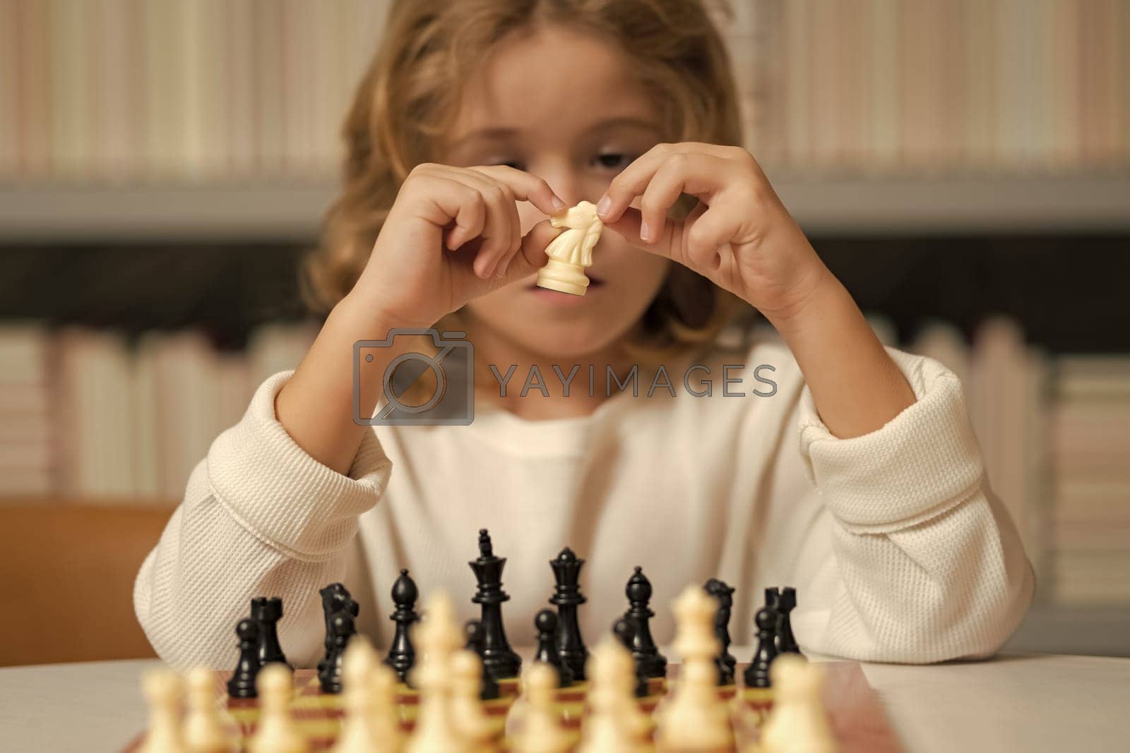 Royalty free image of Little kid chessman play chess game, checkmate. Child playing chess in the room. by RedFoxStudio