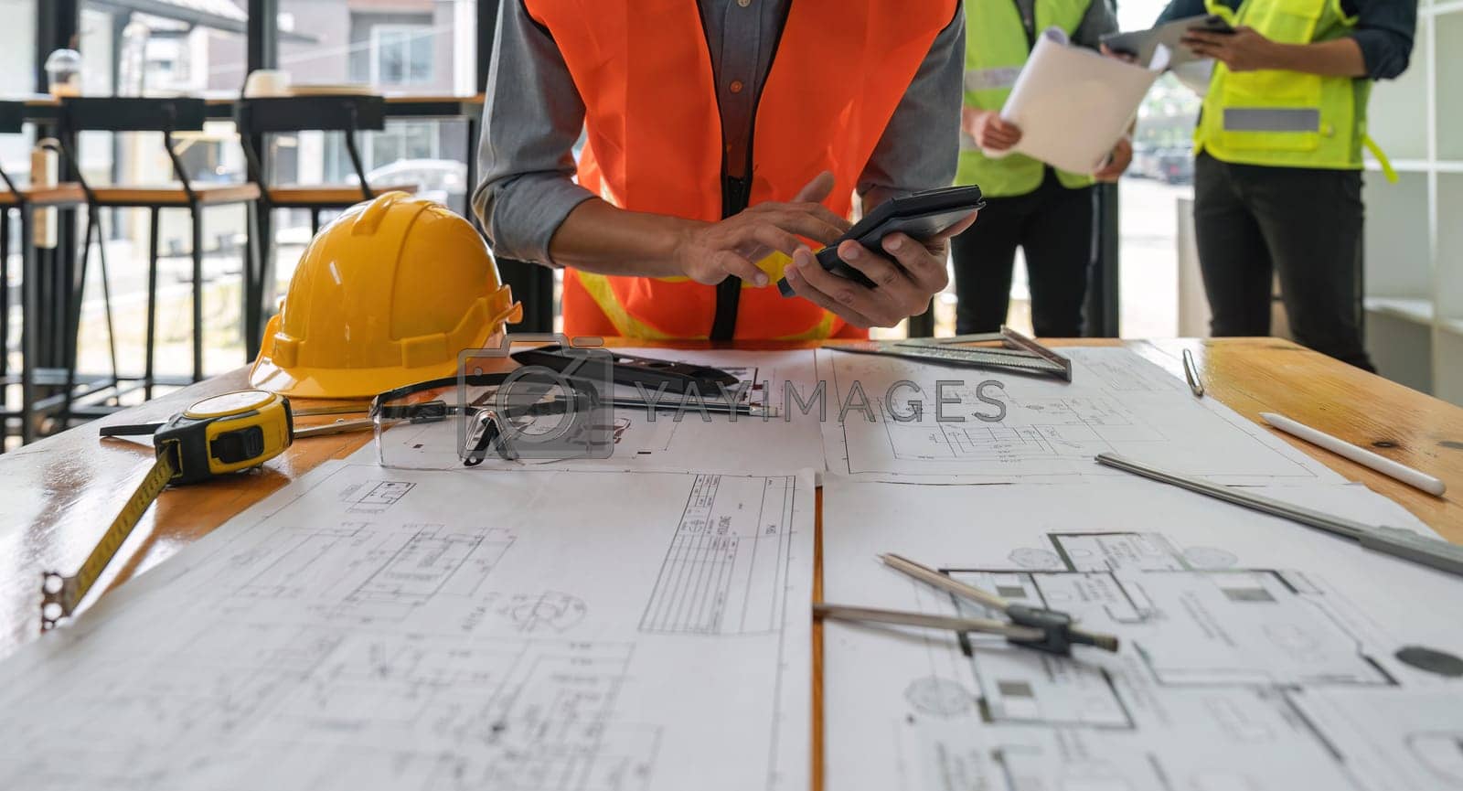 Royalty free image of Engineers working on blueprints and construction plans. Building engineers calculate and draft building construction drawings, civil engineering, and construction business concepts by nateemee