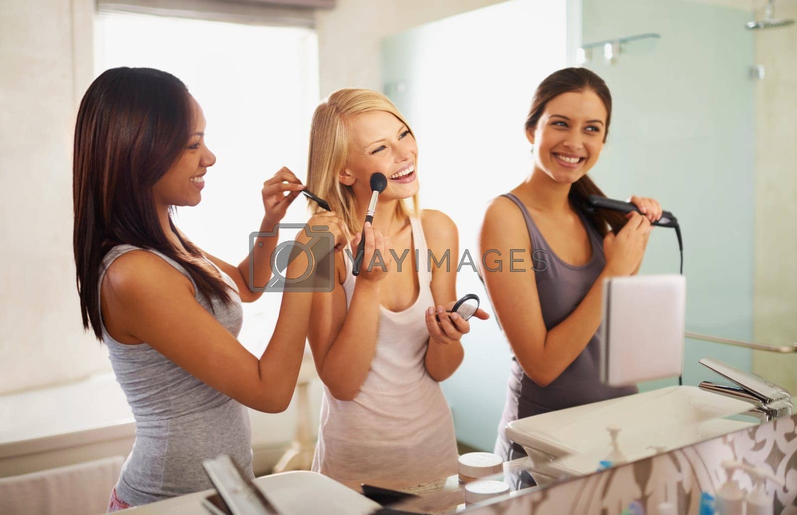 Royalty free image of At the beauty station. Shot of three friends applying makeup in front of the mirror. by YuriArcurs