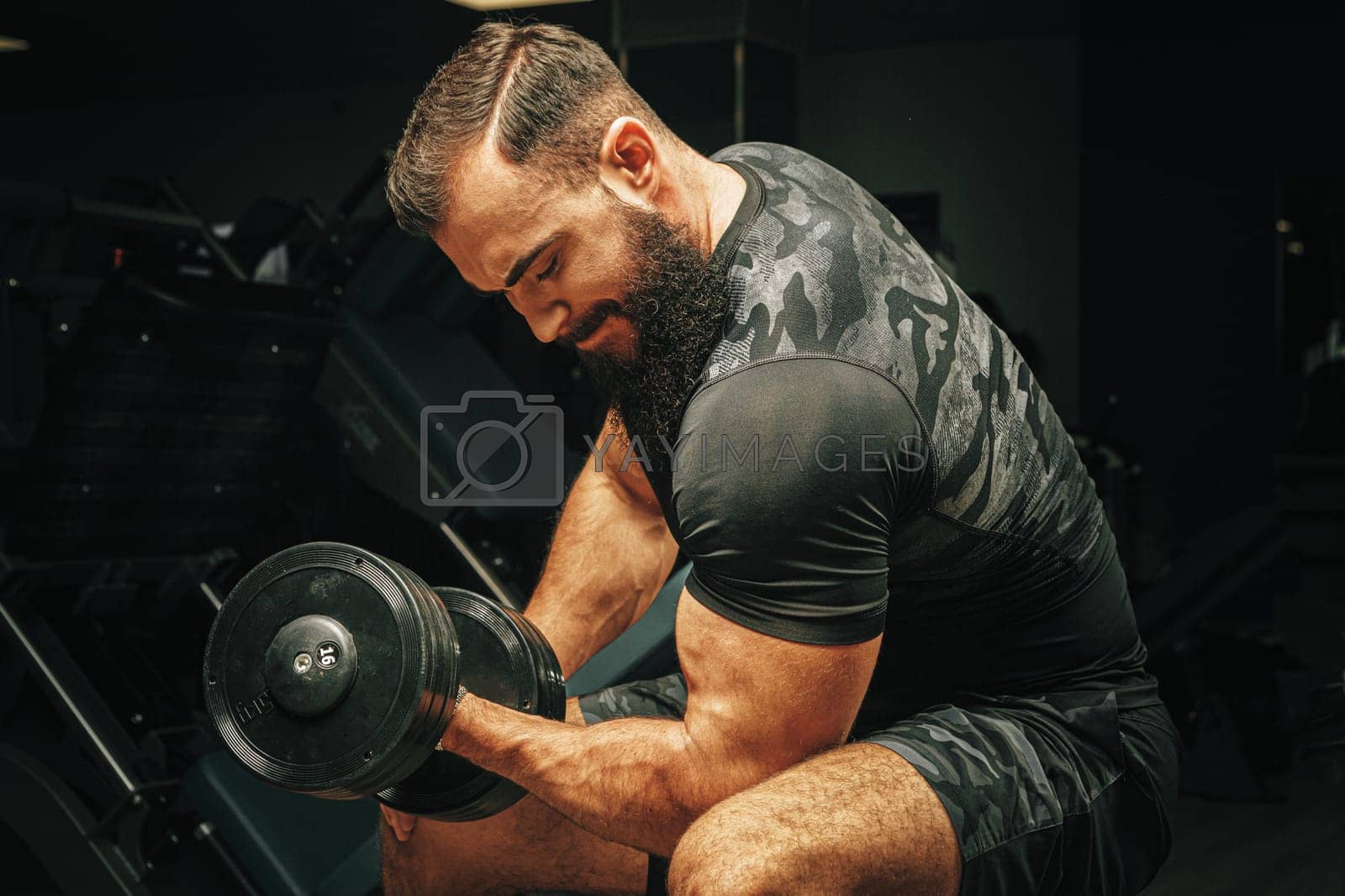 Royalty free image of Male with sport body lifting dumbbells at the gym by Fabrikasimf