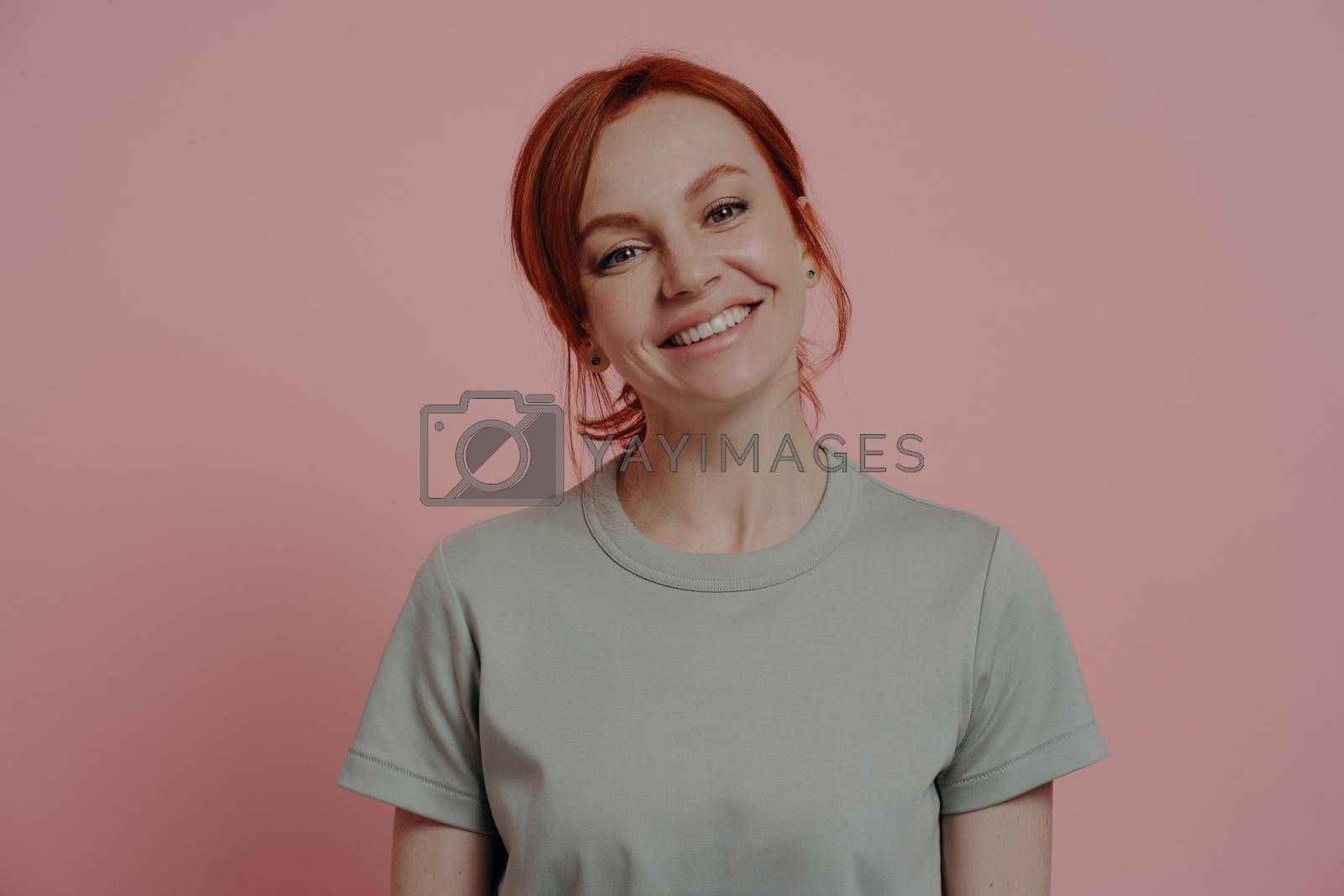 Royalty free image of Positive relaxed redhead woman with pleasant appearance smiling cheerfully, isolated on pink by vkstock