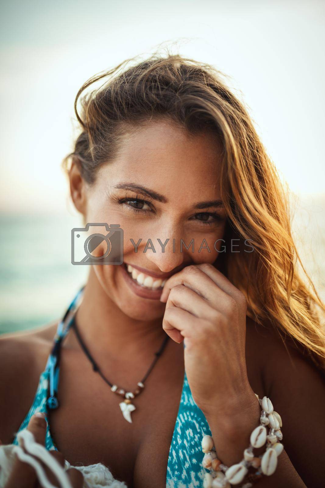 Portrait of an attractive young woman is posing and relaxing at the tropical beach. Looking at camera.