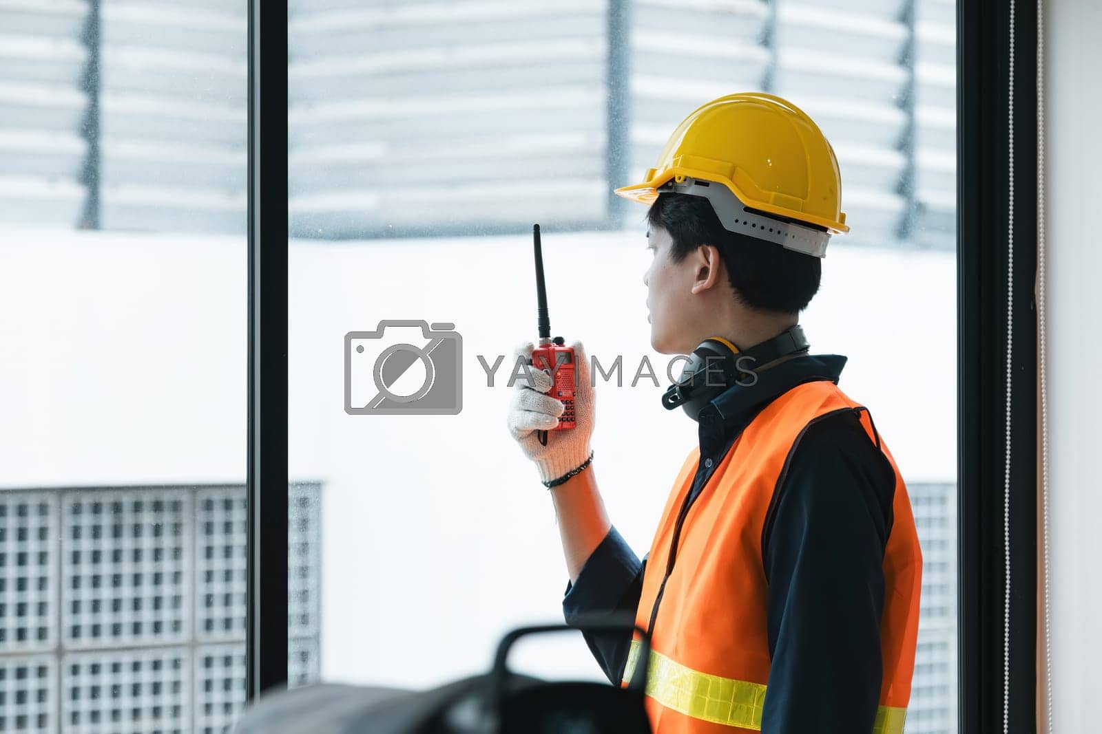 Royalty free image of Young Asian engineer talking radio walkie talkie to operate and control the worker employee to build construction. by nateemee