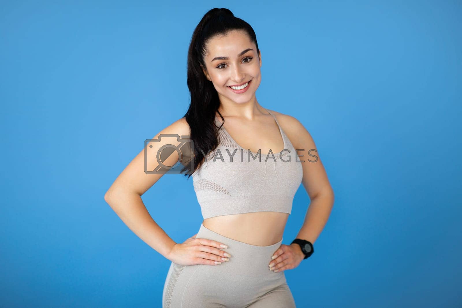 Royalty free image of Attractive young sporty lady posing on blue background by Prostock-studio