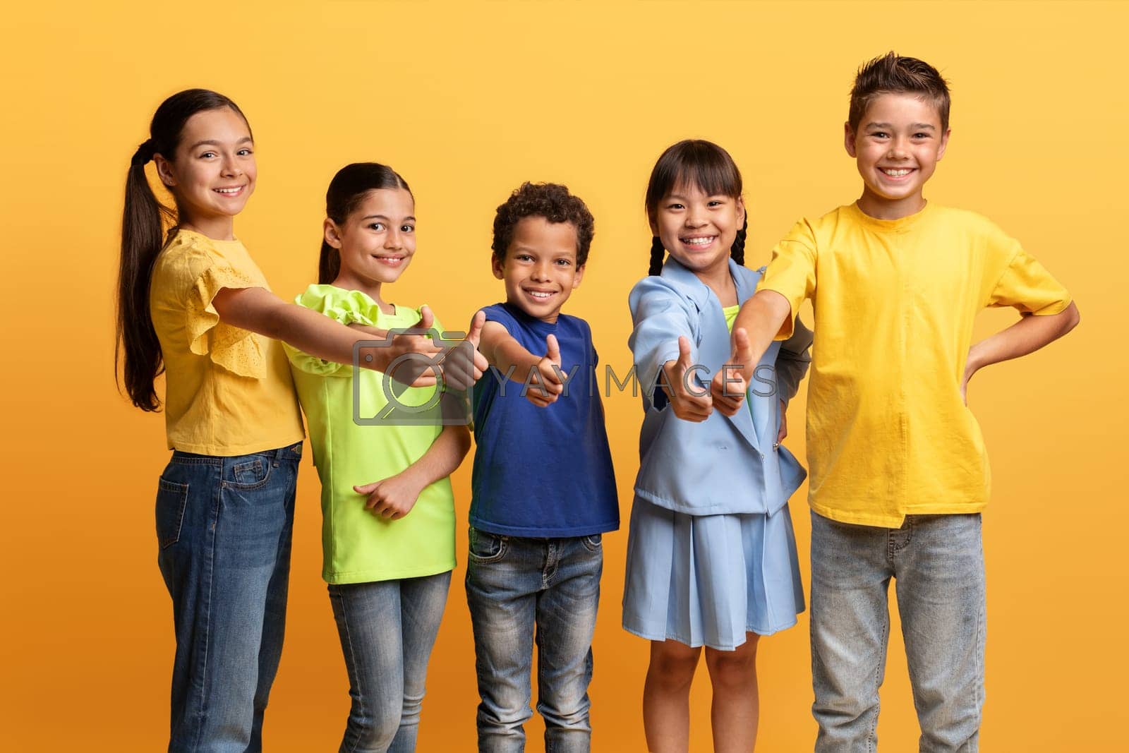 Royalty free image of Happy diverse multietnic children showing thumb up, yellow background by Prostock-studio
