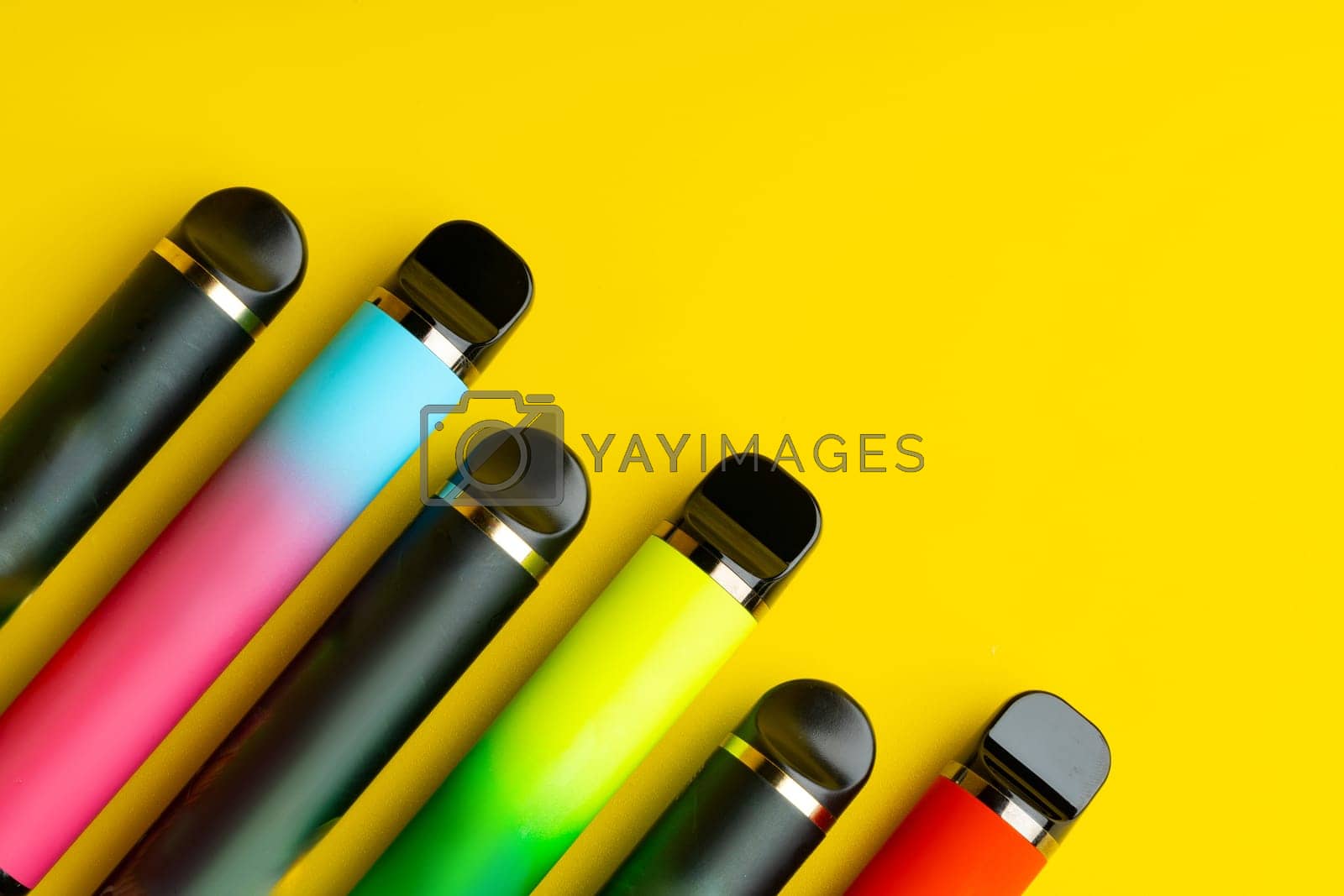 Royalty free image of Colorful disposable electronic cigarettes on yellow background by Fabrikasimf