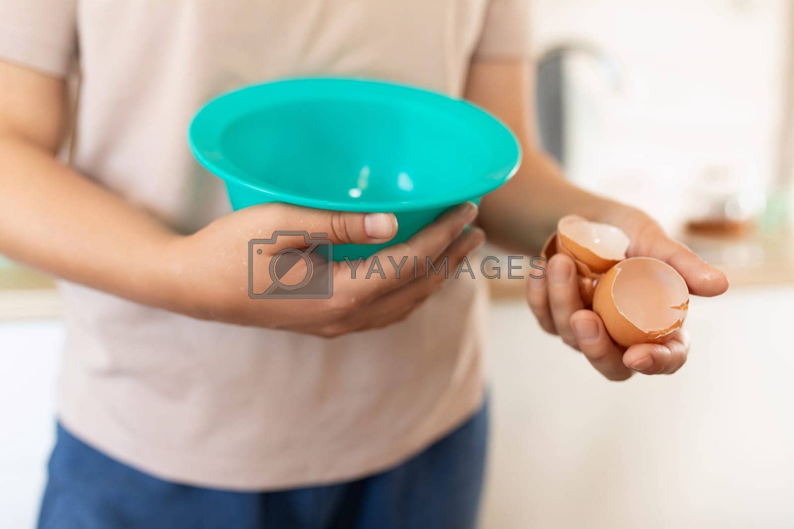 Royalty free image of A woman breaks eggs into a deep bowl by TRMK