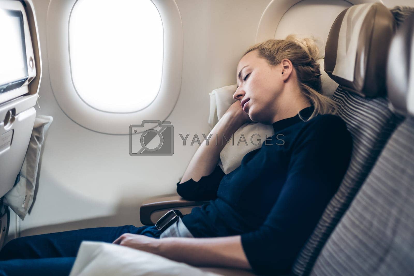 Royalty free image of Tired blonde casual caucasian woman napping on airplane. by kasto