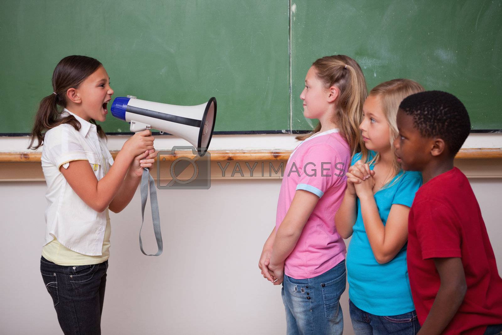 Royalty free image of Angry schoolgirl screaming through a megaphone to her classmates by Wavebreakmedia