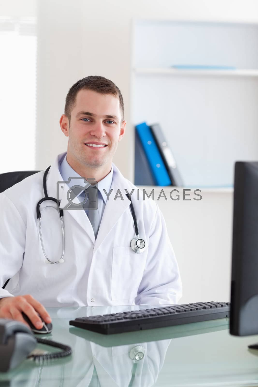 Royalty free image of Smiling doctor sitting on his computer by Wavebreakmedia
