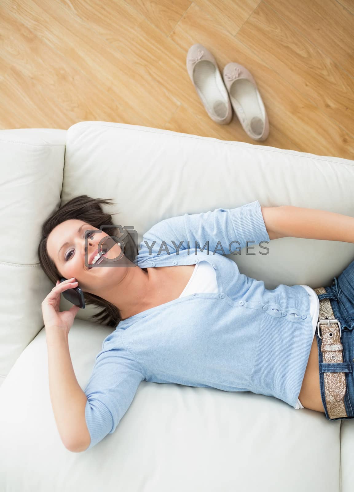 Royalty free image of Smiling woman calling and lying back on sofa by Wavebreakmedia