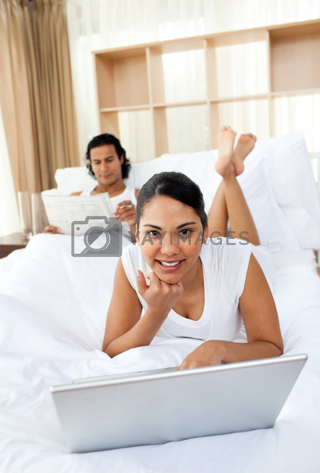 Royalty free image of Attractive woman lying on the bed using a laptop  by Wavebreakmedia