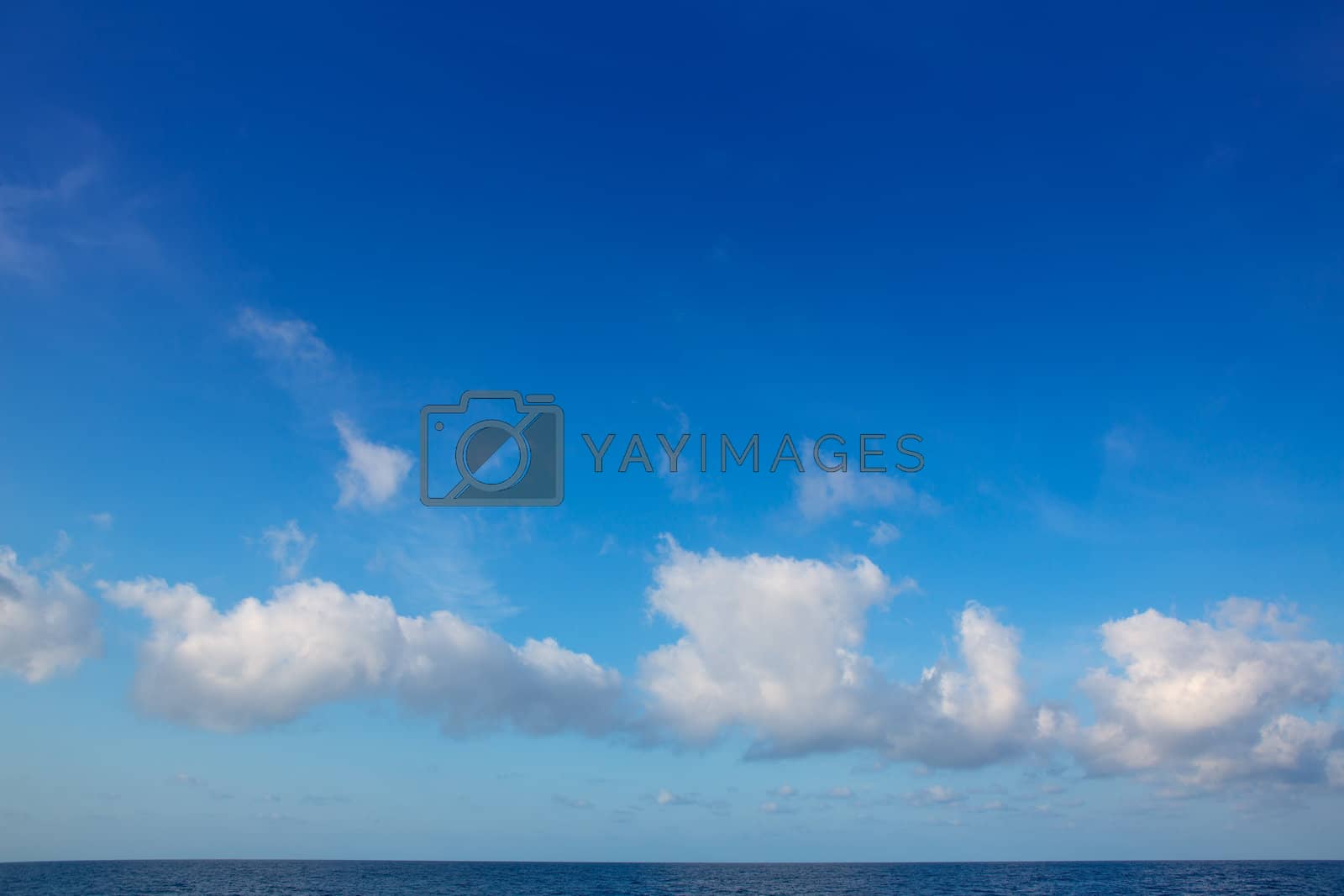 Royalty free image of cumulus clouds in blue sky over water horizon by lunamarina