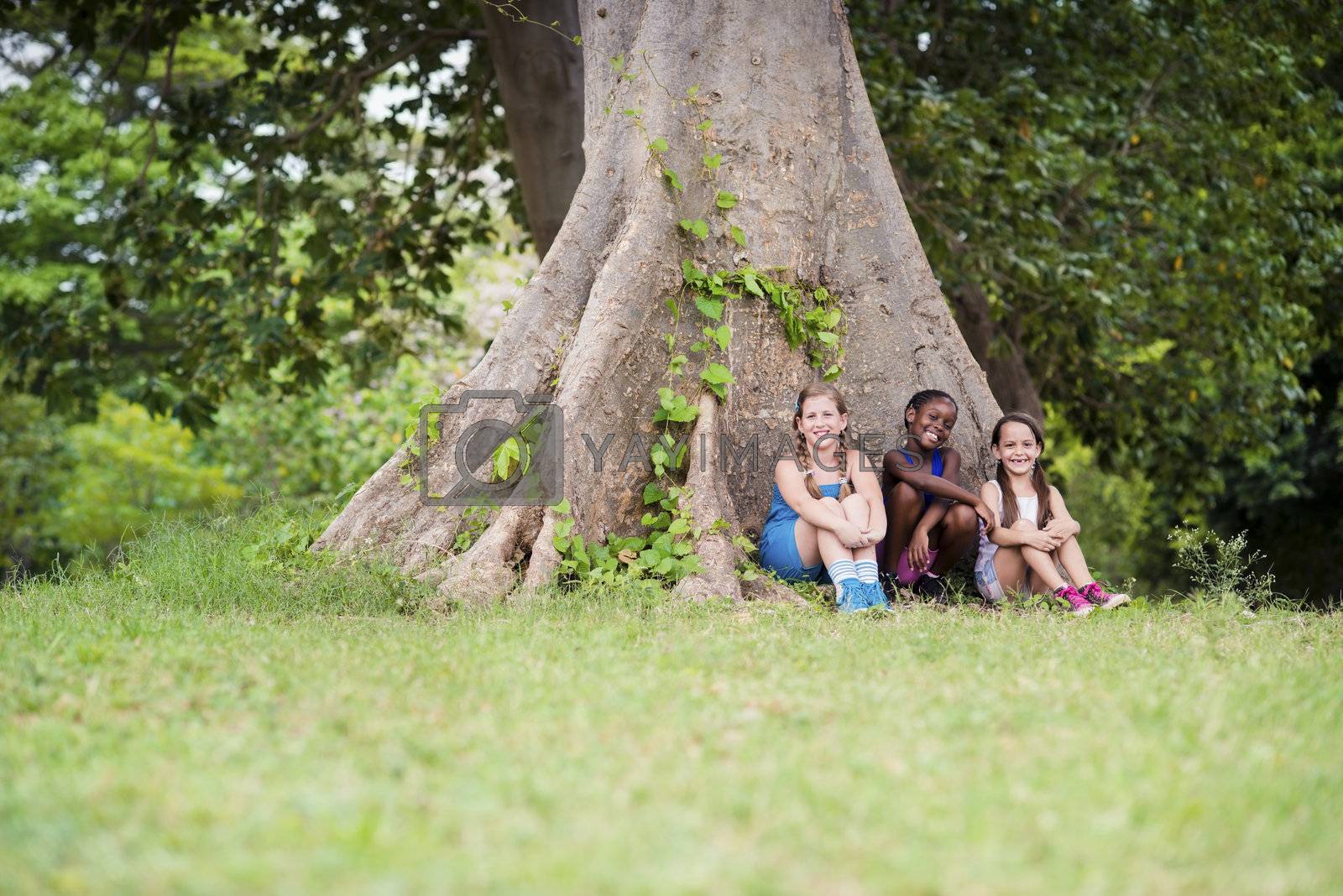 Royalty free image of Three happy female friends sitting near big tree by diego_cervo