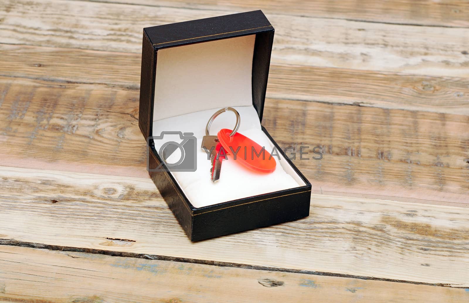 Royalty free image of key with blank tag in black gift box on wooden background by inxti