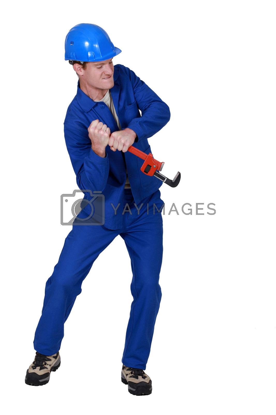 Royalty free image of Tradesman trying to force open an object using a pipe wrench by phovoir