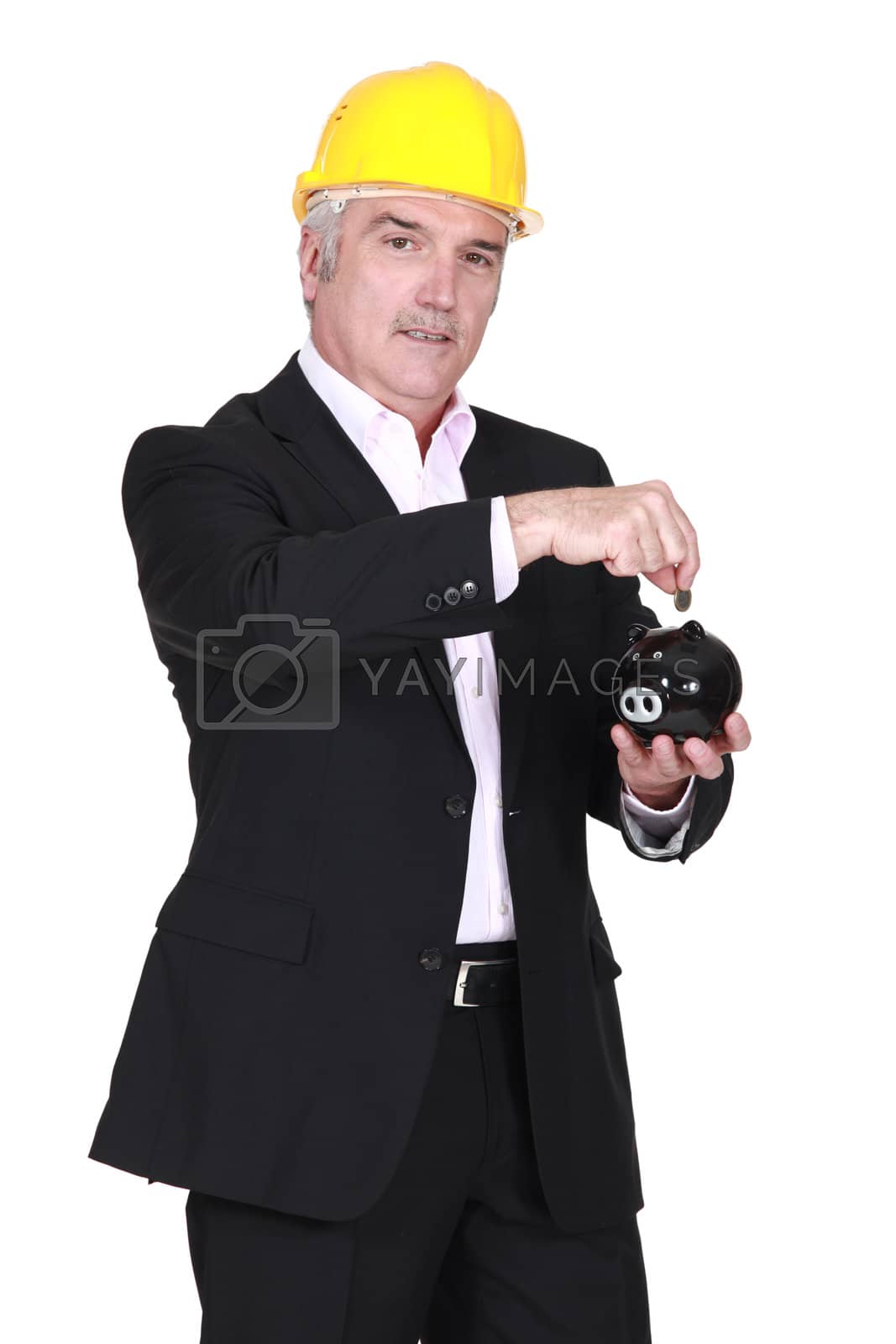 Royalty free image of Engineer putting his savings into a piggy bank by phovoir