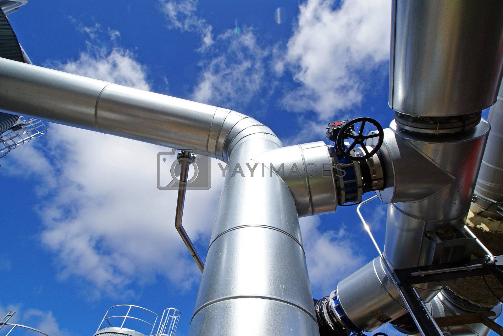 Royalty free image of industrial piping and valves against blue sky by nostal6ie