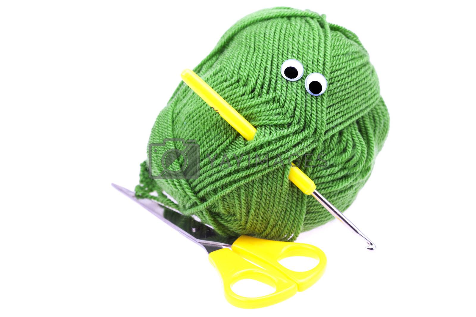Royalty free image of skein of wool  with eyes, scissors and crochet hooks isolated on by jannyjus
