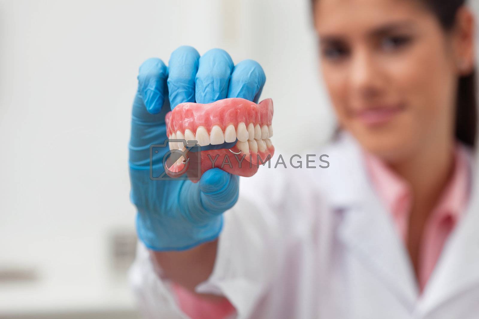 Royalty free image of Female dentist holding dental mold by leaf