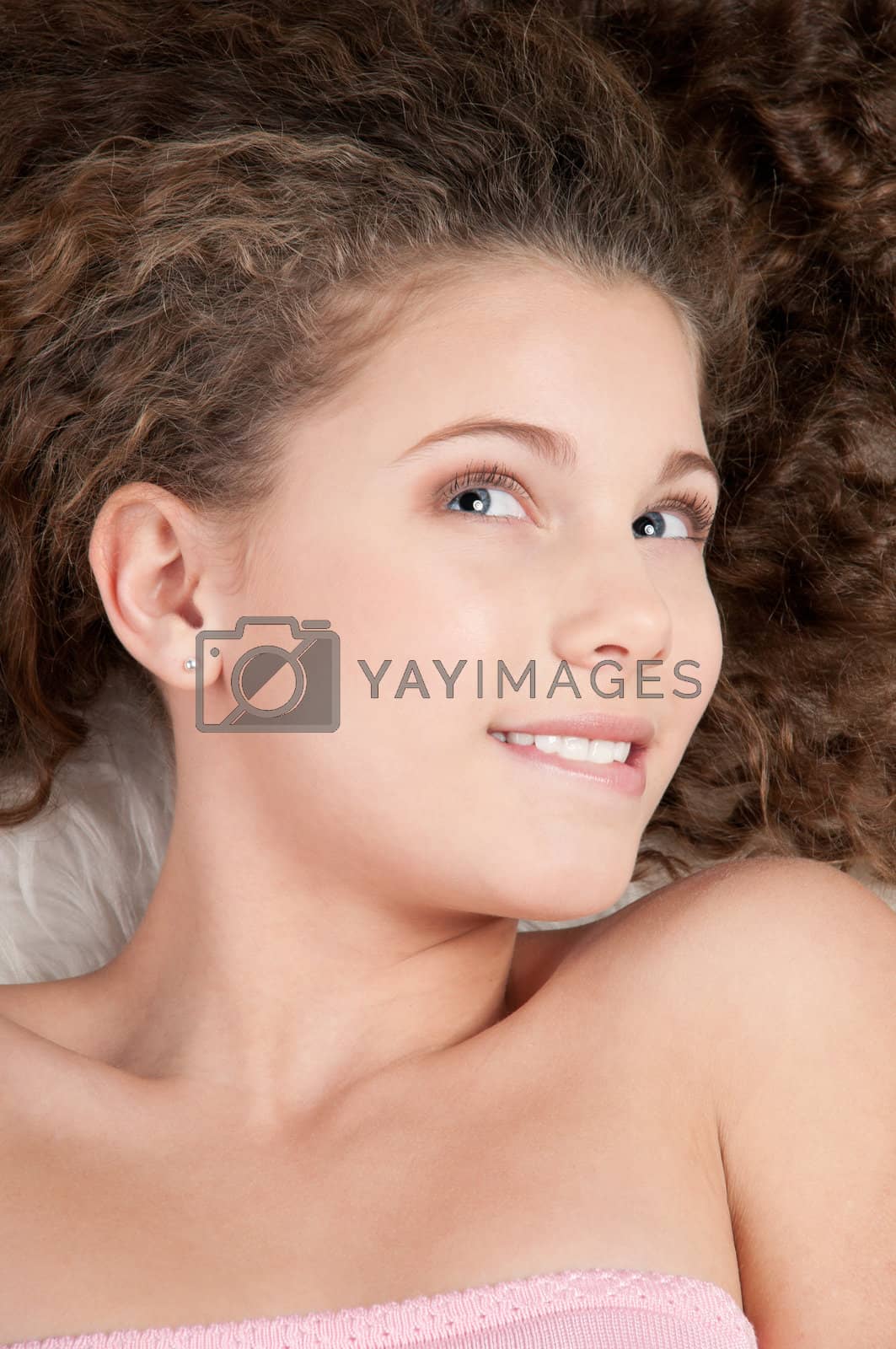 Royalty free image of Girl with perfect curly hair lying on fur bed by markin