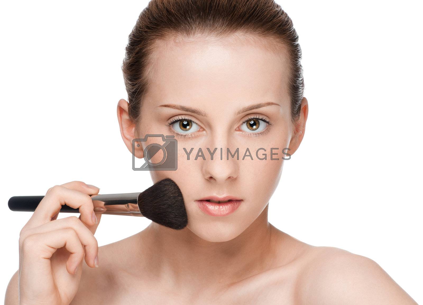 Royalty free image of Beautiful young adult woman applying cosmetic brush by markin