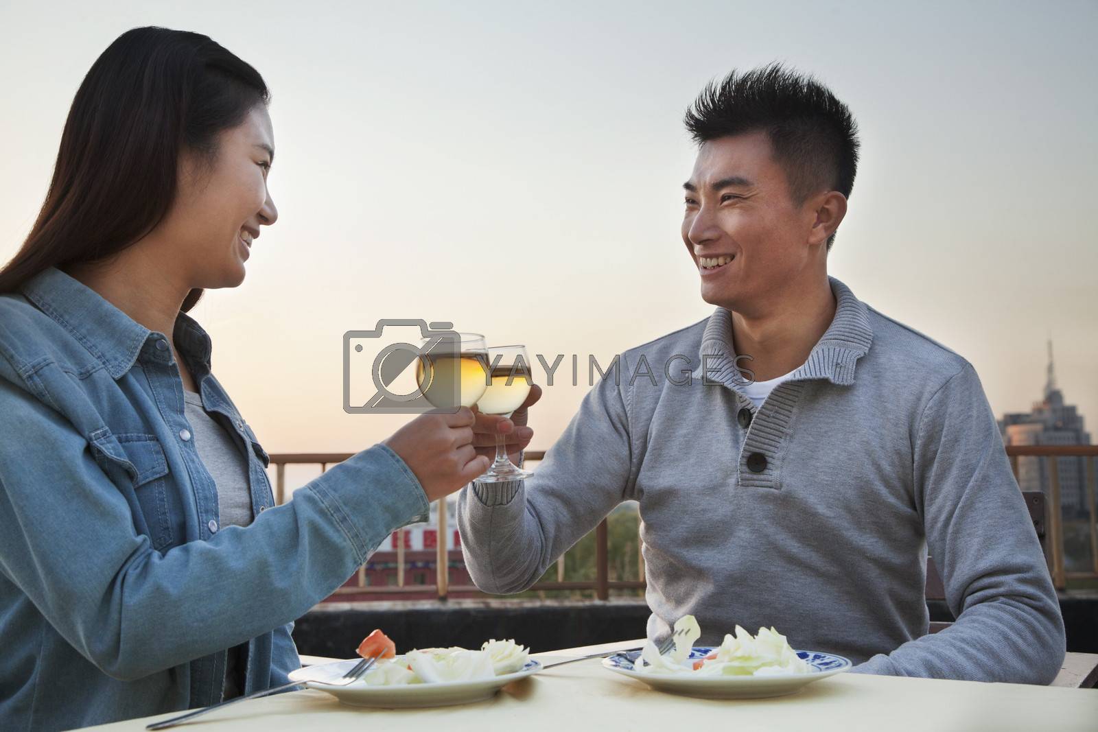 Royalty free image of Young couple eating on the roof top, toast  by XiXinXing