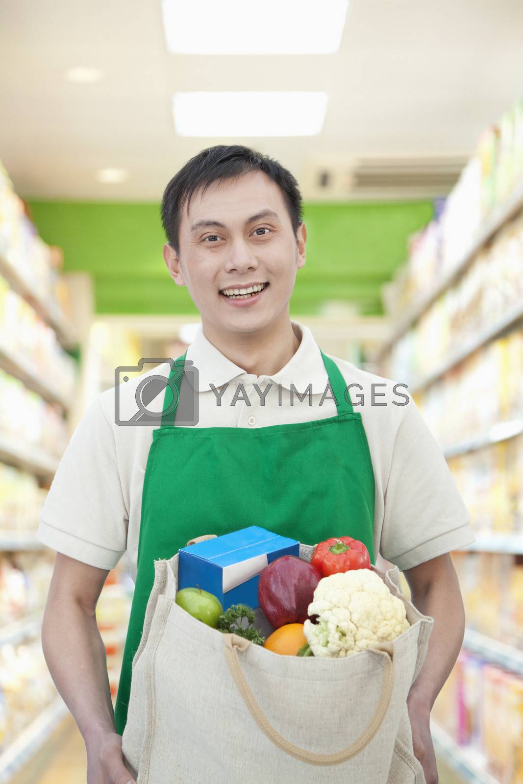 Royalty free image of Young Man Holding Shopping Bag with Fruits and Vegetables by XiXinXing