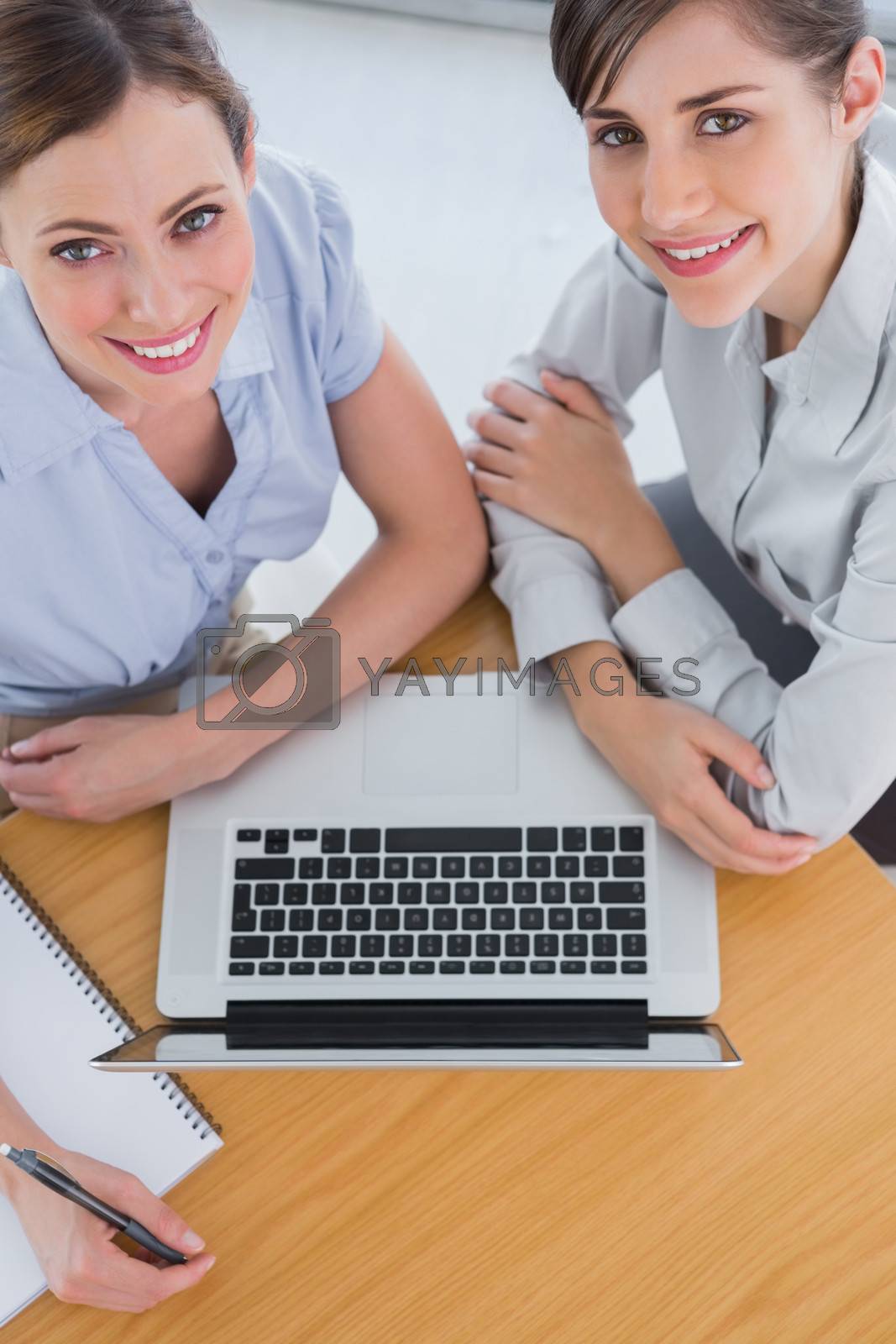 Royalty free image of Businesswomen having a meeting and smiling up at camera by Wavebreakmedia