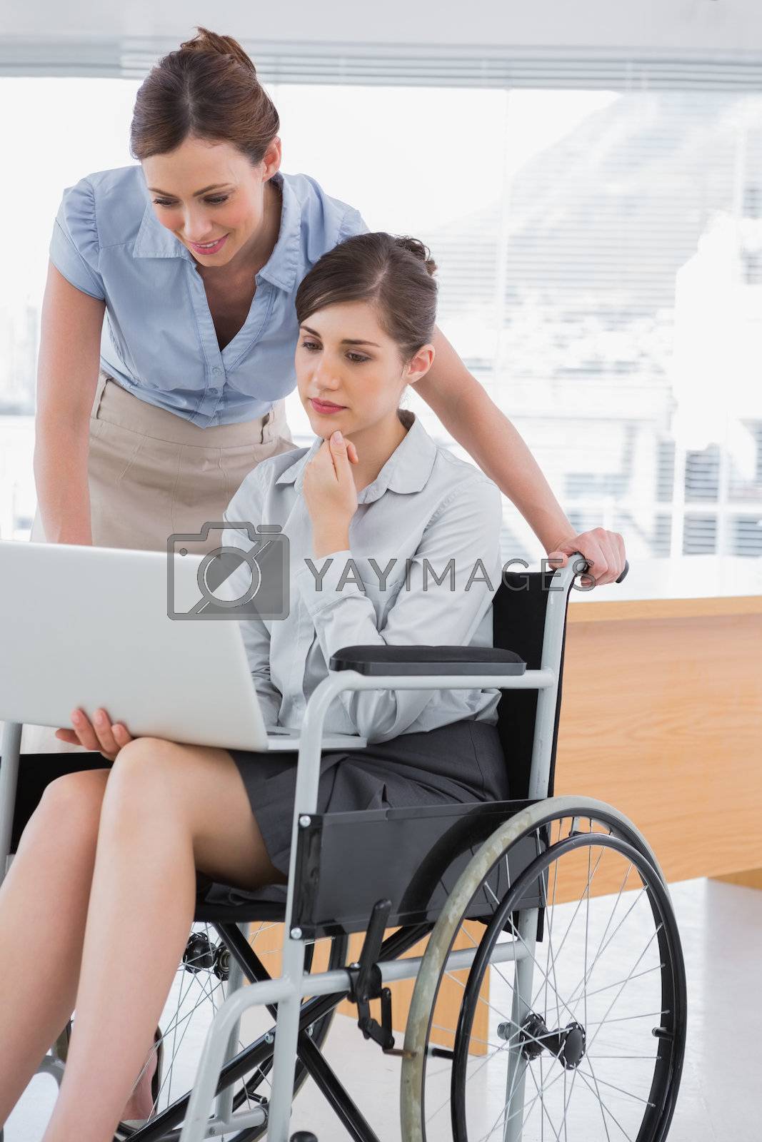 Royalty free image of Disabled businesswoman looking at laptop with her colleague by Wavebreakmedia