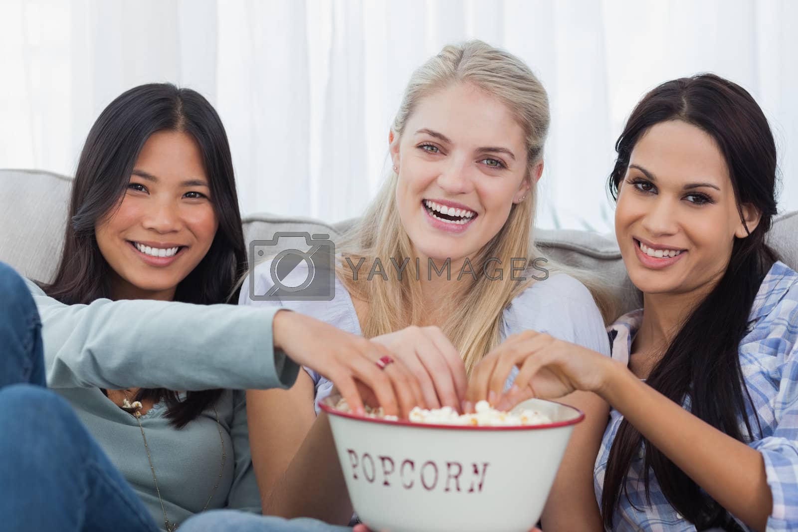 Royalty free image of Friends sharing bowl of popcorn and watching tv by Wavebreakmedia