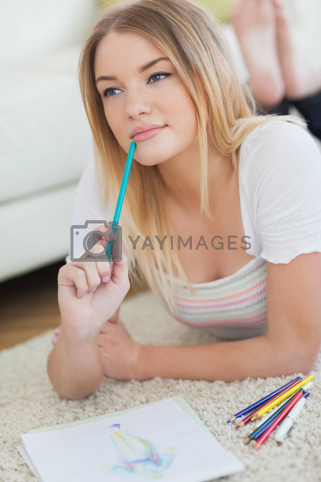 Royalty free image of Thoughtful woman lying on floor looking for inspiration by Wavebreakmedia