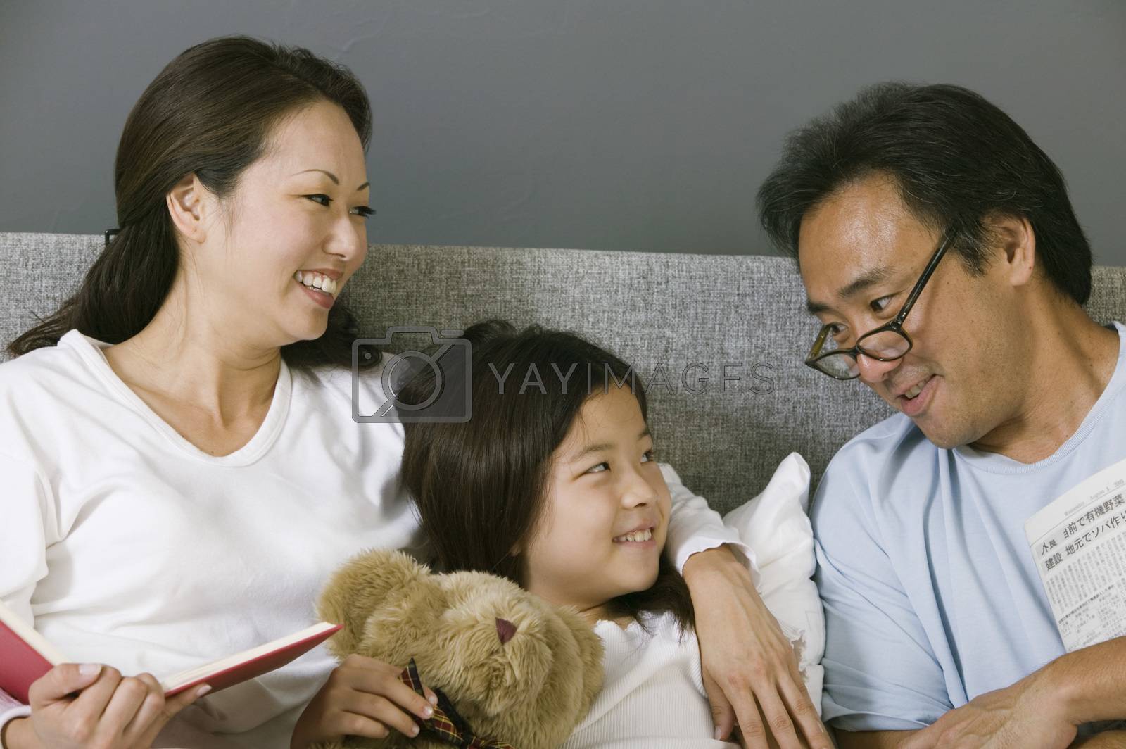 Mother and father relaxing in bed with daughter