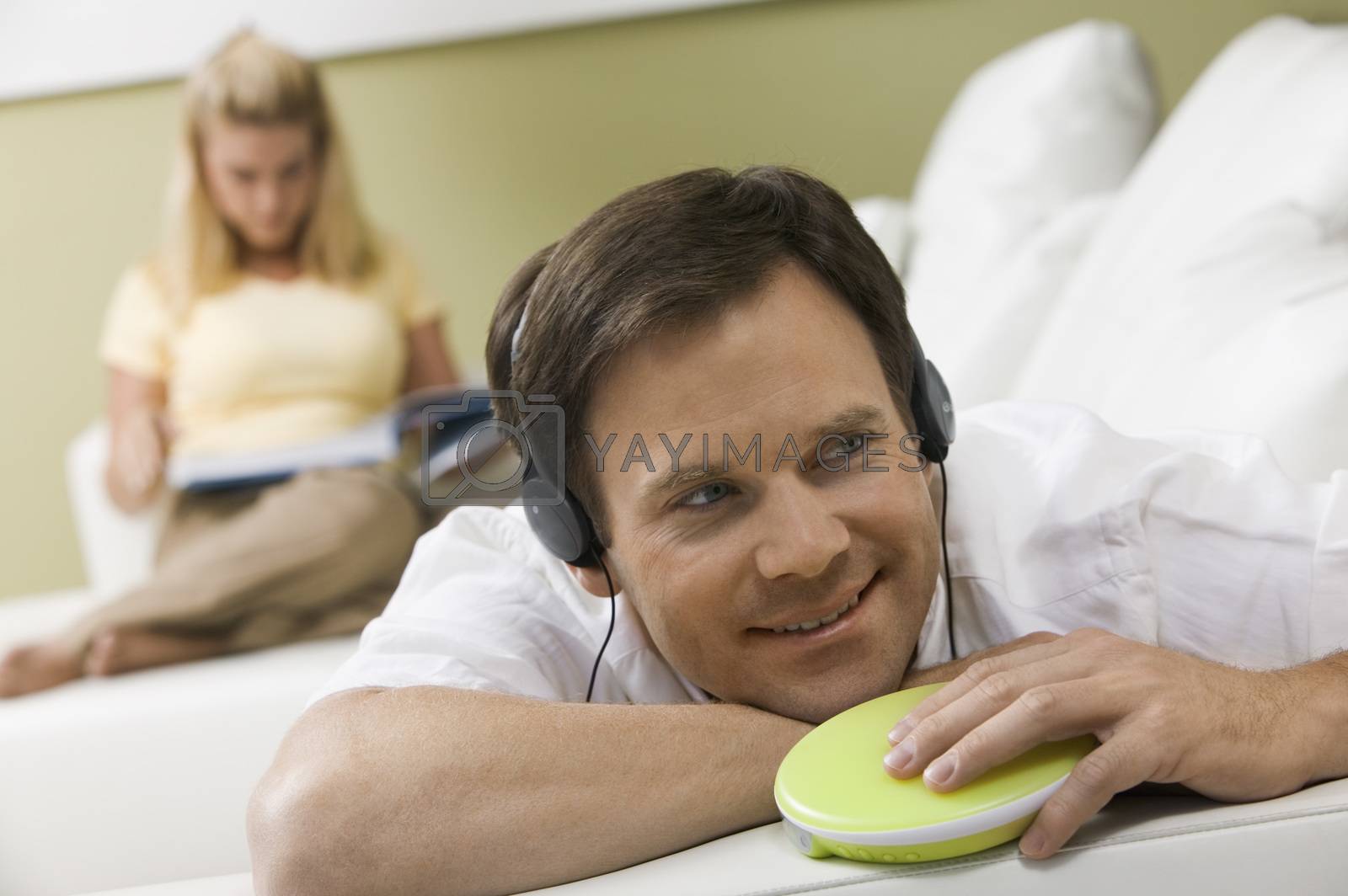 Royalty free image of Man Listening to Music While Wife Reads by moodboard